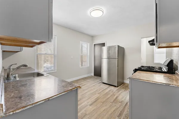 a kitchen with stainless steel appliances granite countertop a refrigerator a sink a stove and countertops with wooden floor