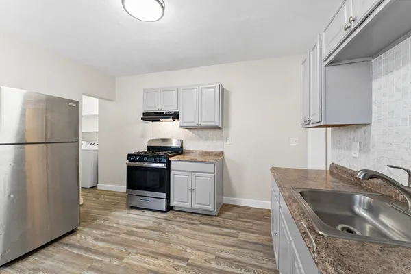 a kitchen with granite countertop a sink stove and refrigerator