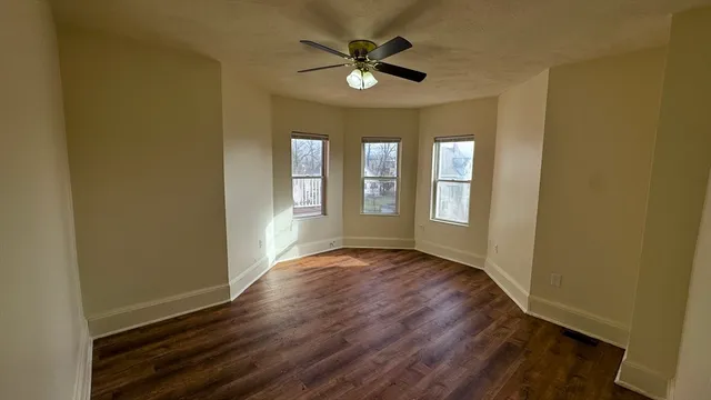 a view of an empty room with window and wooden floor
