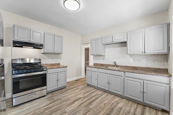 a kitchen with stainless steel appliances granite countertop a stove a sink and white cabinets