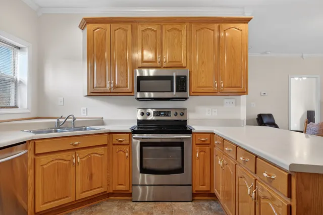 a kitchen with granite countertop a sink stainless steel appliances wooden cabinets and a window