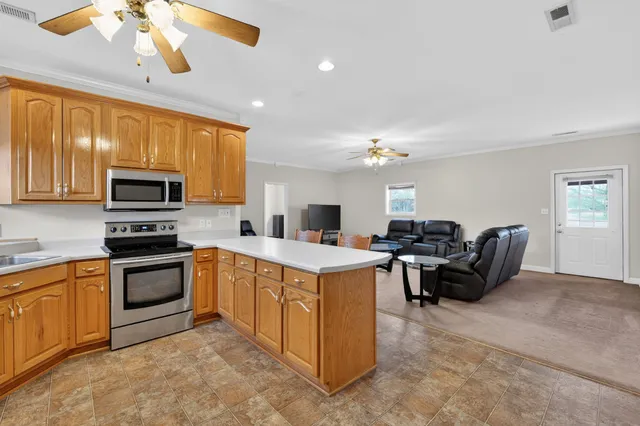 a kitchen with a stove a microwave and living room view