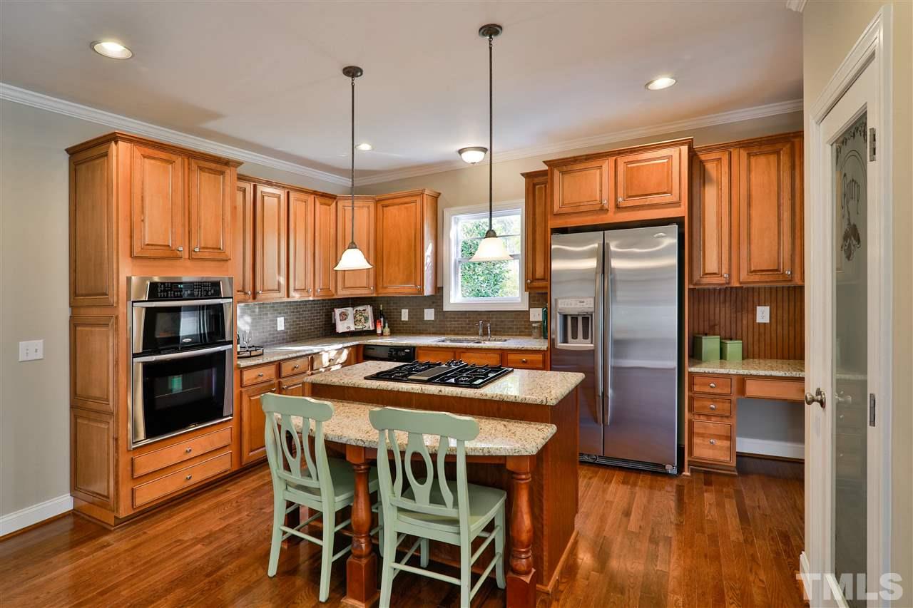 5741 Spring Glen Lane Raleigh, NC 27616 - Photo 5 of 25 a kitchen with stainless steel appliances granite countertop a stove a refrigerator a kitchen island a table and chairs
