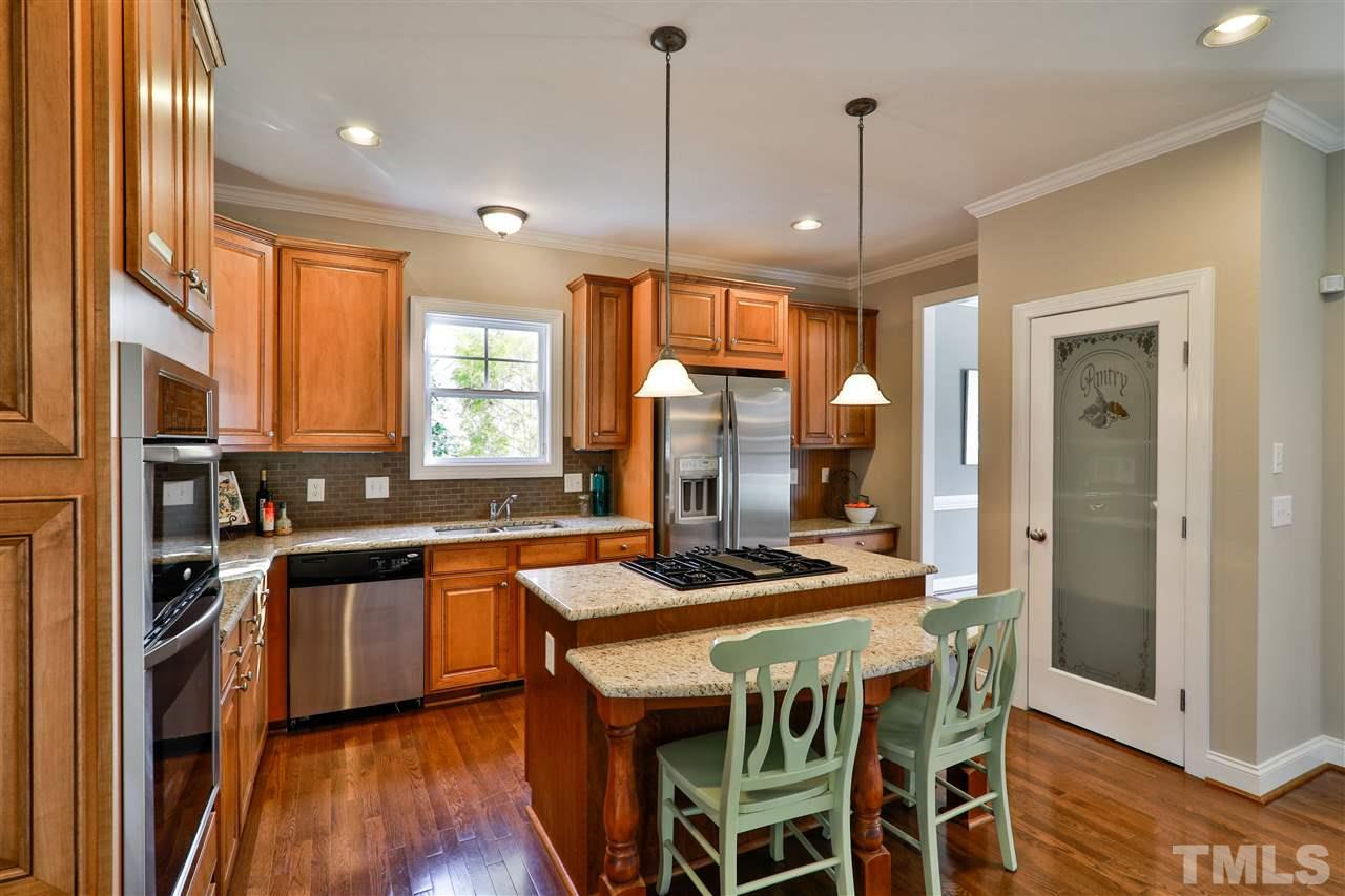 5741 Spring Glen Lane Raleigh, NC 27616 - Photo 6 of 25 a kitchen with stainless steel appliances granite countertop a stove a sink dishwasher a refrigerator and a dining table with wooden floor