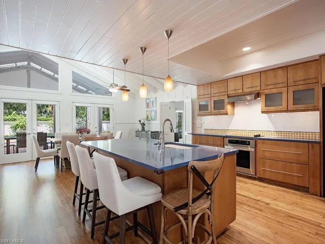 a dining hall with stainless steel appliances kitchen island granite countertop wooden floor a dining table and chairs