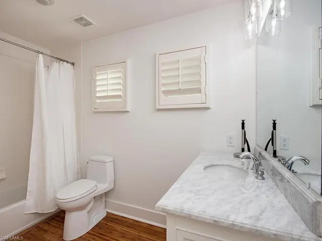 a bathroom with a granite countertop sink toilet and mirror