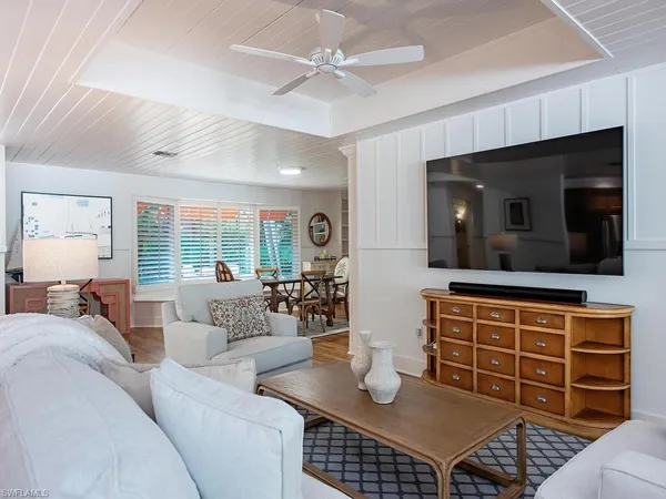 a living room with furniture a flat screen tv and kitchen view