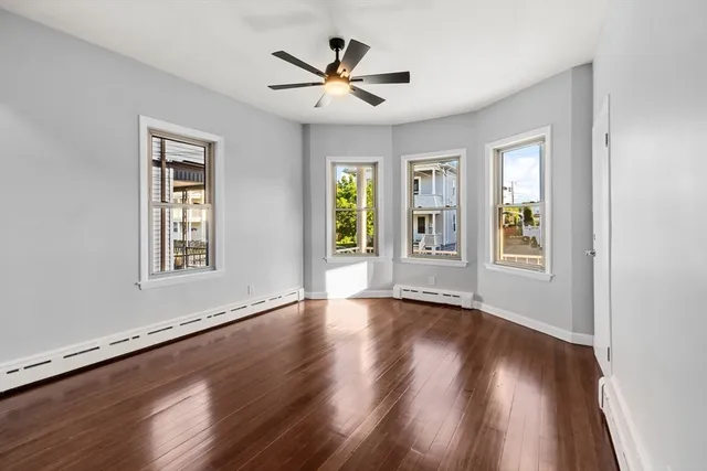 a view of an empty room with window and wooden floor