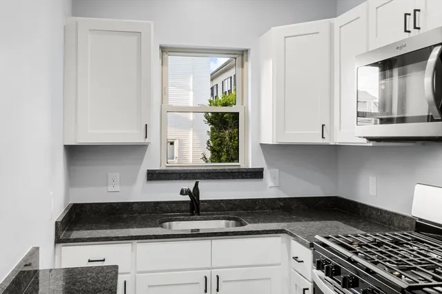 a kitchen with granite countertop white cabinets and a stove