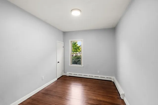 a view of an empty room with wooden floor and window