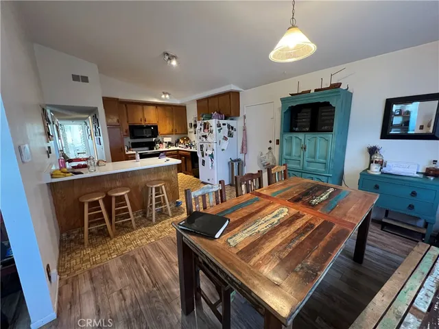 a kitchen with stainless steel appliances granite countertop a stove top oven a sink a dining table and chairs with wooden floor