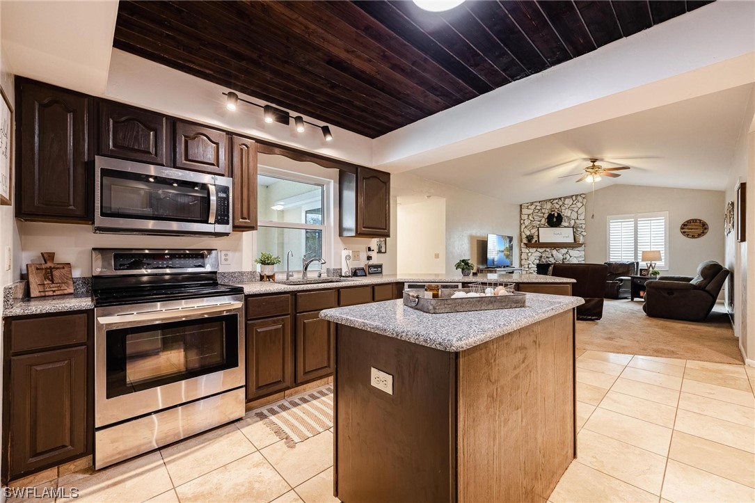 1367 Frontier Circle LaBelle, FL 33935 - Photo 15 of 37 a kitchen with stainless steel appliances kitchen island granite countertop a stove top oven a sink dishwasher a dining table and chairs with the wooden floor