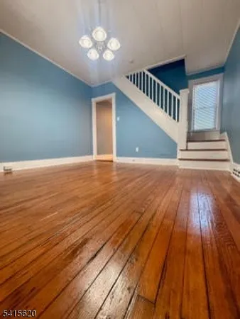 a view of an empty room with wooden floor and a chandelier