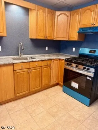 a kitchen with granite countertop a stove a sink and a microwave