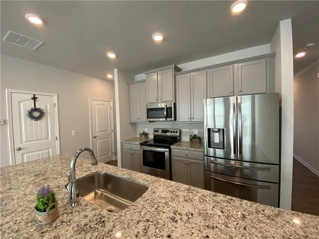 a kitchen with granite countertop a refrigerator and a sink