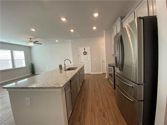 a kitchen with stainless steel appliances granite countertop a refrigerator a sink and a stove