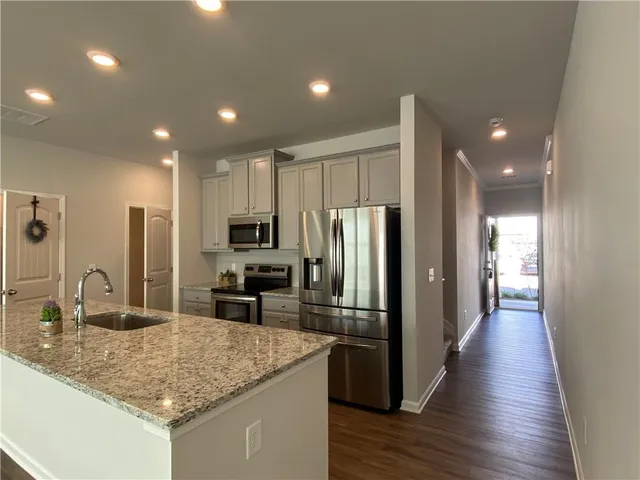 a kitchen with stainless steel appliances granite countertop a sink refrigerator and cabinets