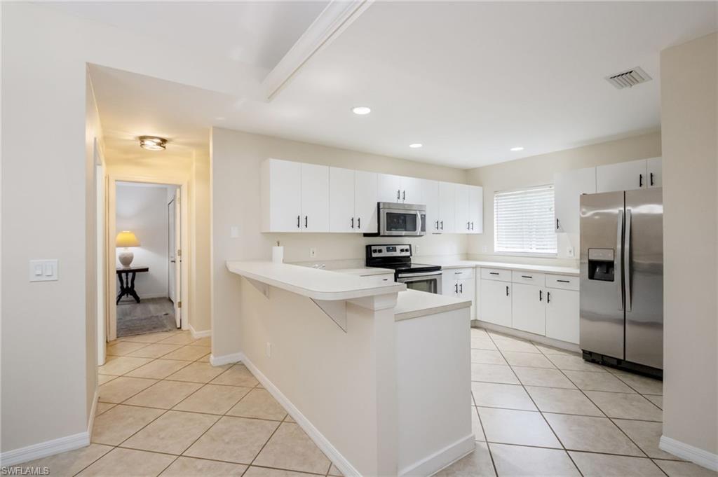 2910 2nd Street Northeast Naples, FL 34120 - Photo 11 of 36 a kitchen with white cabinets and refrigerator