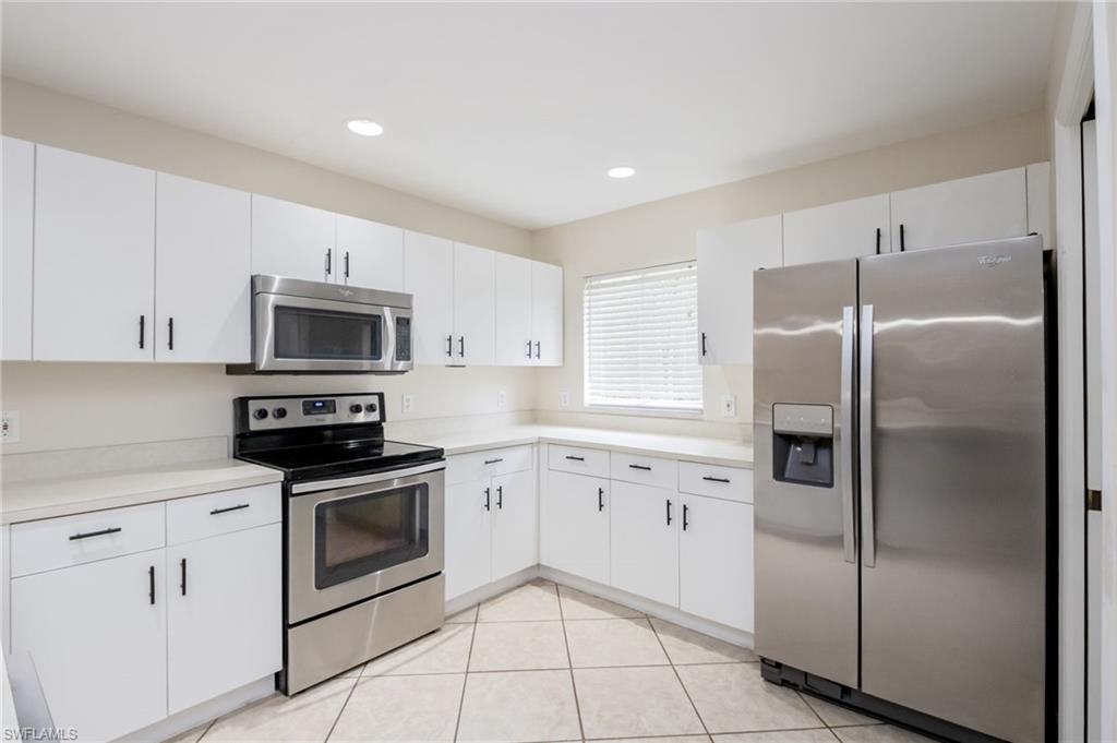 2910 2nd Street Northeast Naples, FL 34120 - Photo 12 of 36 a kitchen with granite countertop white cabinets and stainless steel appliances