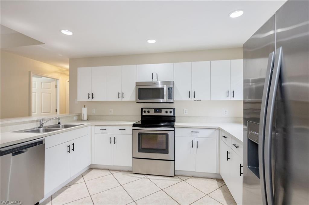 2910 2nd Street Northeast Naples, FL 34120 - Photo 13 of 36 a kitchen with white cabinets stainless steel appliances and sink