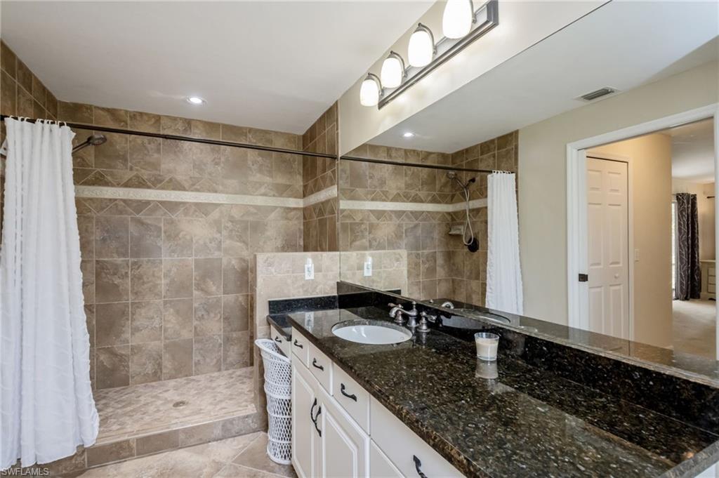 2910 2nd Street Northeast Naples, FL 34120 - Photo 22 of 36 a bathroom with a granite countertop sink a mirror and shower