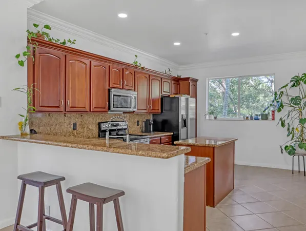 a kitchen with stainless steel appliances granite countertop a stove a sink a refrigerator and a microwave