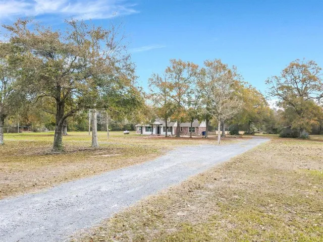 a backyard of a house with large trees and wooden fence