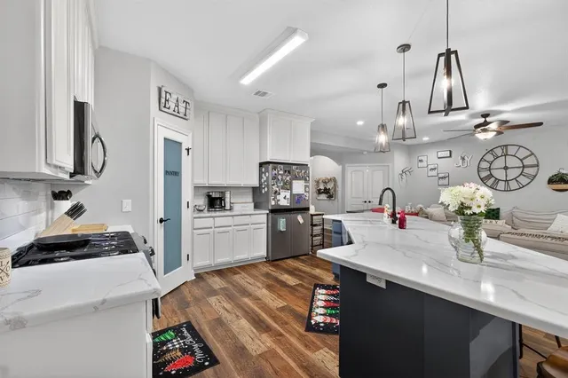 a room with chandelier fan and wooden floor