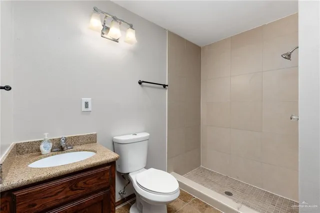 a bathroom with a granite countertop toilet a sink and a mirror