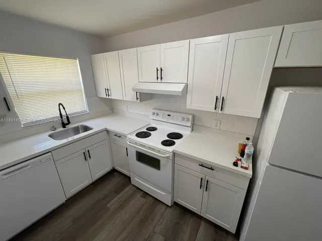 a white kitchen with sink and white appliances