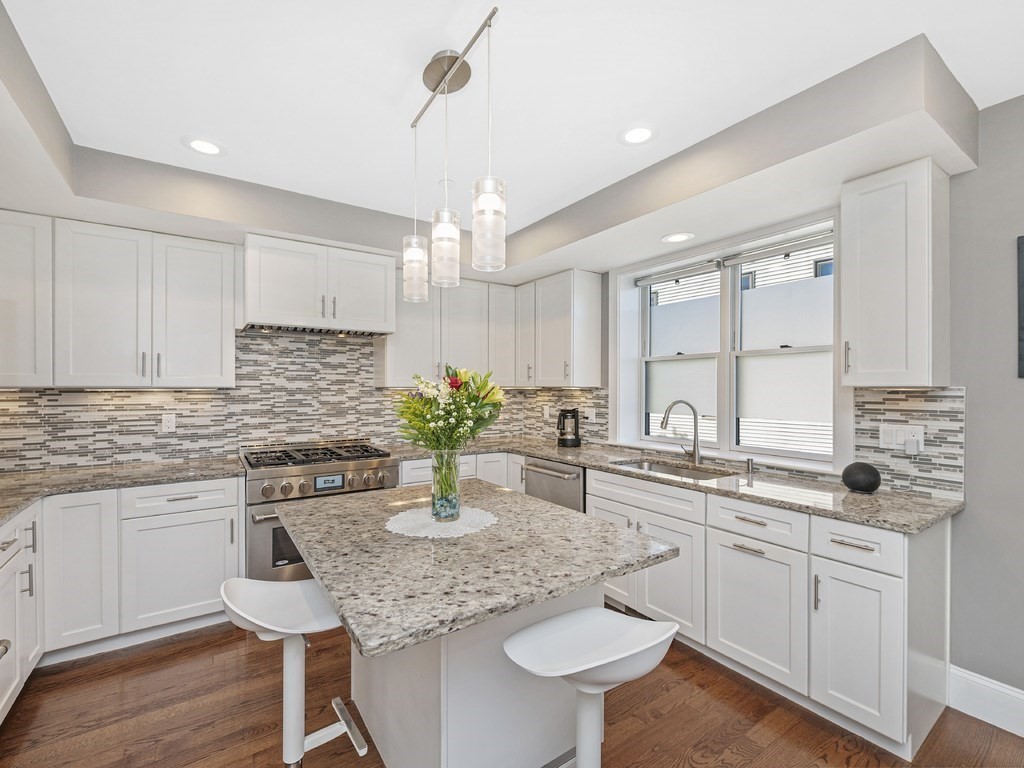 198 California Street, Unit 3 Newton, MA 02458 - Photo 9 of 34 a kitchen with a white center island a sink cabinets and stainless steel appliances