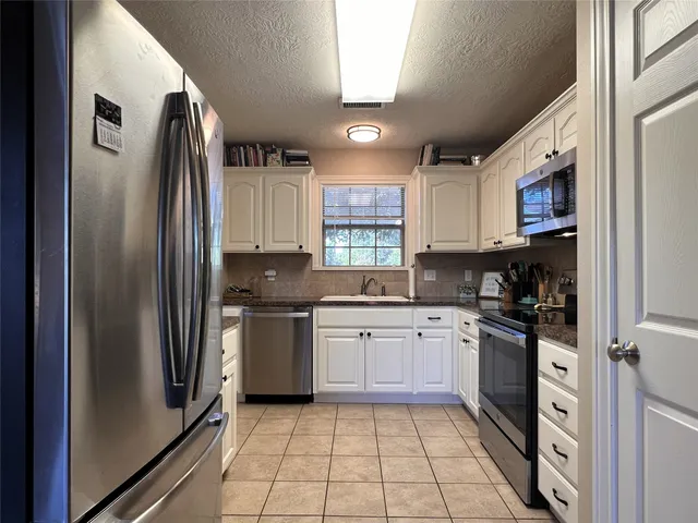 a kitchen with stainless steel appliances granite countertop a stove top oven a sink and a refrigerator