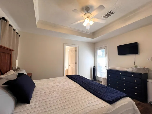 a bedroom with a bed a flat screen tv and a chandelier