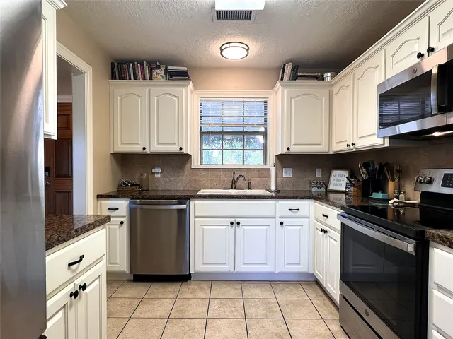 a white kitchen with granite countertop a stove top oven microwave and cabinets