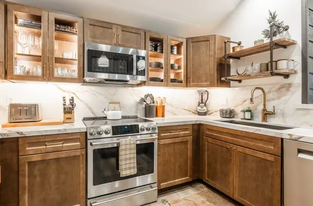 a kitchen with stainless steel appliances granite countertop a stove a sink and a microwave