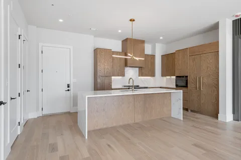 a large kitchen with kitchen island a refrigerator a sink dishwasher a stove and a wooden floors