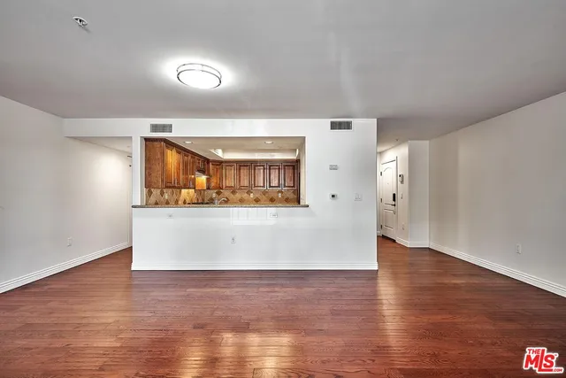 a view of a big room with wooden floor and windows