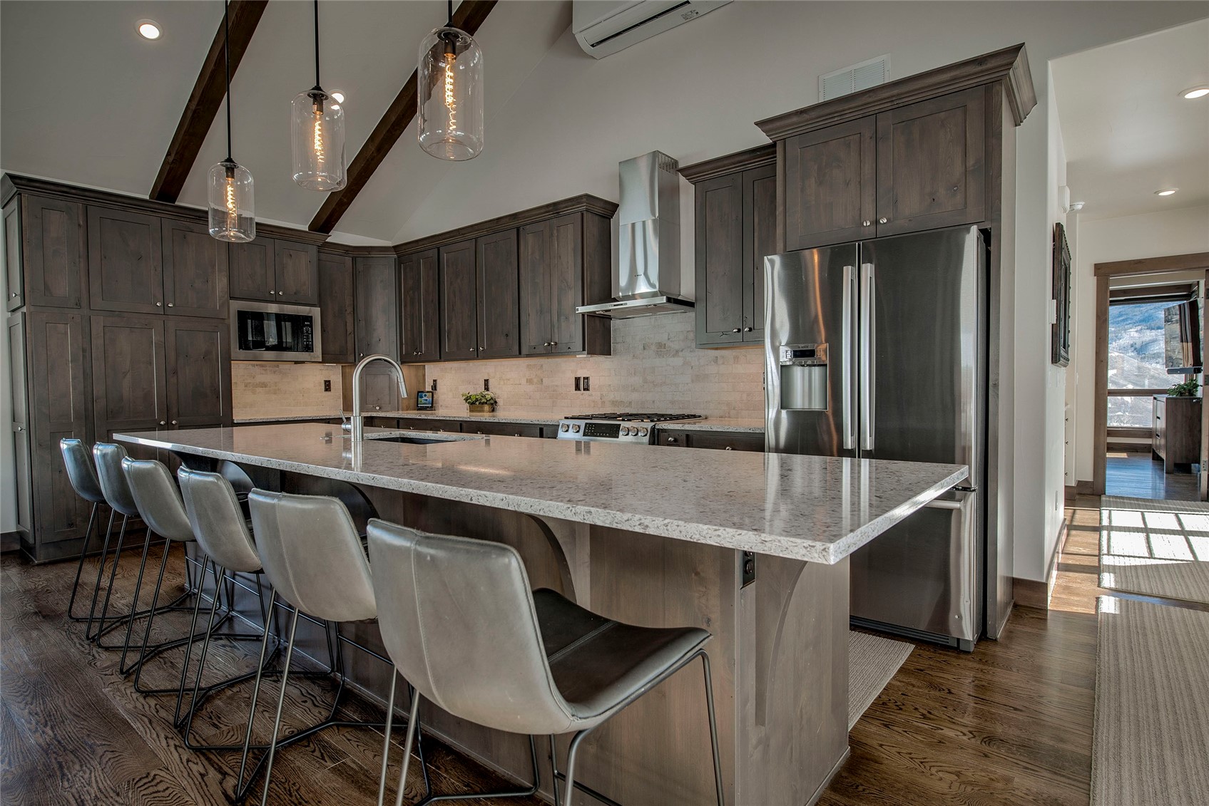 307 Maryland Creek Road Silverthorne, CO 80498 - Photo 6 of 47 Kitchen with light stone counters, a kitchen island with sink, and dark wood-style flooring.