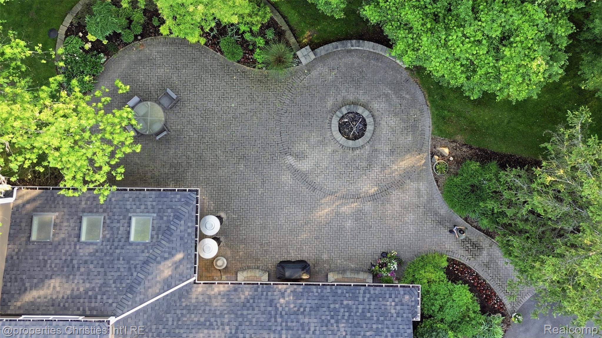 25235 Canterbury Road Franklin, MI 48025 - Photo 52 of 56 Expansive paver patio featuring a built-in fire pit, surrounded by mature trees and landscaping