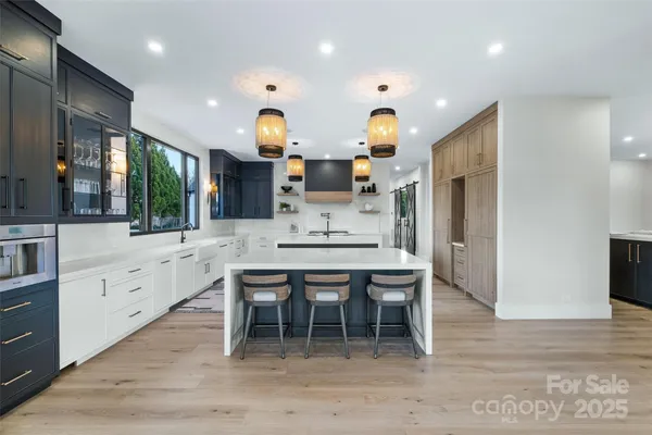 a kitchen with stainless steel appliances kitchen island granite countertop a table chairs sink and cabinets
