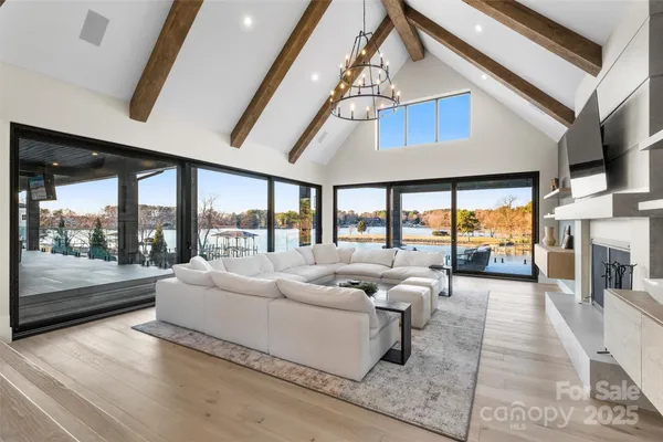 a living room with furniture large windows and a chandelier