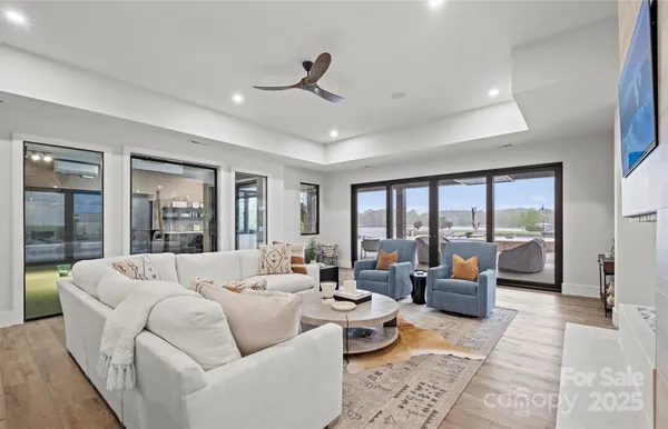 a living room with couches and kitchen view with wooden floor