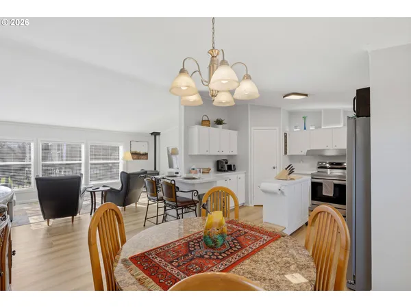 a living room with couches a dining table and kitchen view with wooden floor