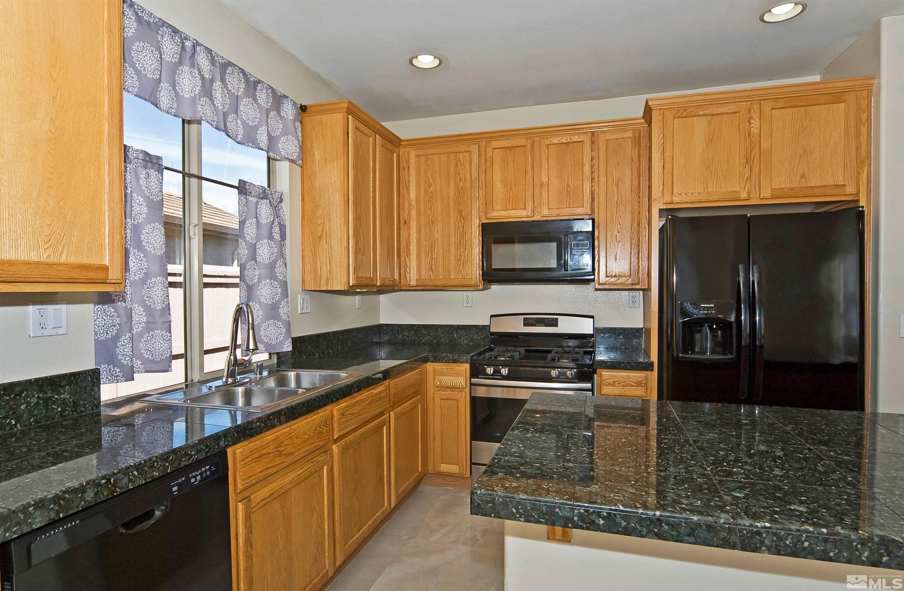 10620 Fire Poppy Circle Reno, NV 89521 - Photo 6 of 25 a kitchen with stainless steel appliances granite countertop a stove a sink a microwave a refrigerator and cabinets