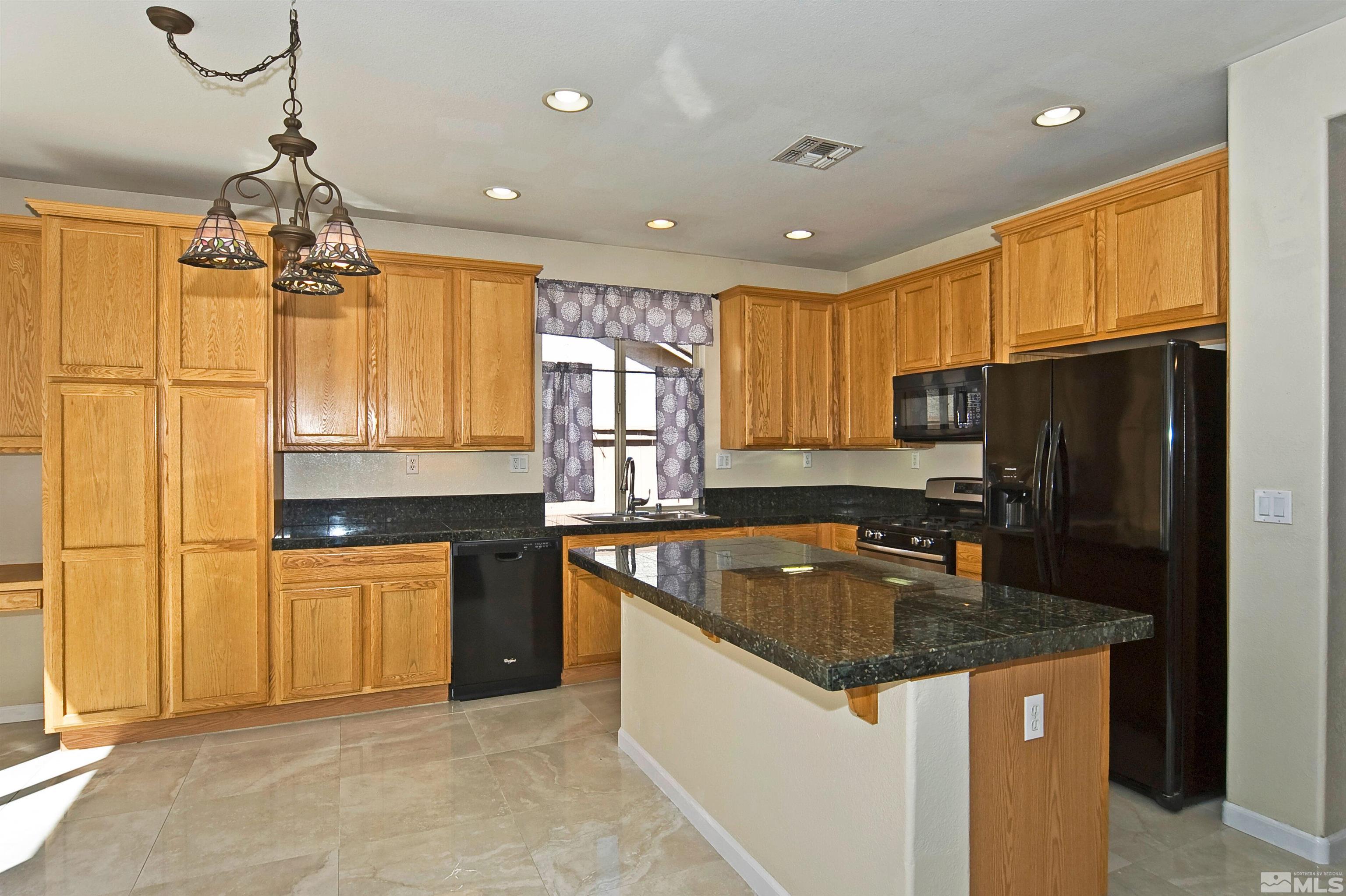 10620 Fire Poppy Circle Reno, NV 89521 - Photo 8 of 25 a kitchen with granite countertop stainless steel appliances a sink stove refrigerator and cabinets