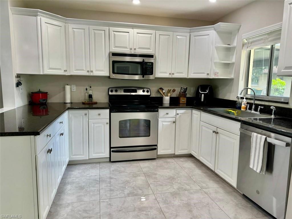 857 Palm View Drive, Unit 32 Naples, FL 34110 - Photo 3 of 9 a white kitchen with stainless steel appliances granite countertop a sink a stove a microwave and cabinets