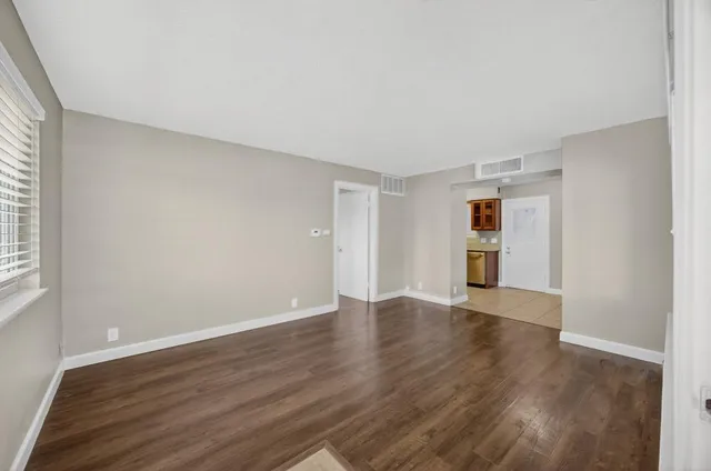 a view of an empty room with wooden floor and a window