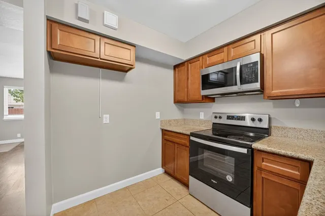 a kitchen with granite countertop a stove top oven a sink dishwasher and a refrigerator with wooden floor