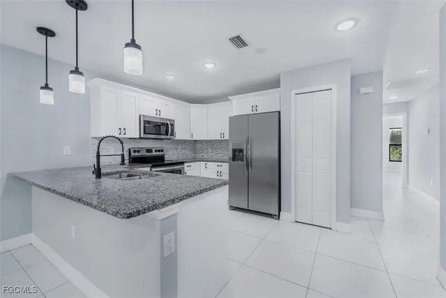 a kitchen with stainless steel appliances granite countertop a refrigerator a sink a stove a microwave and island