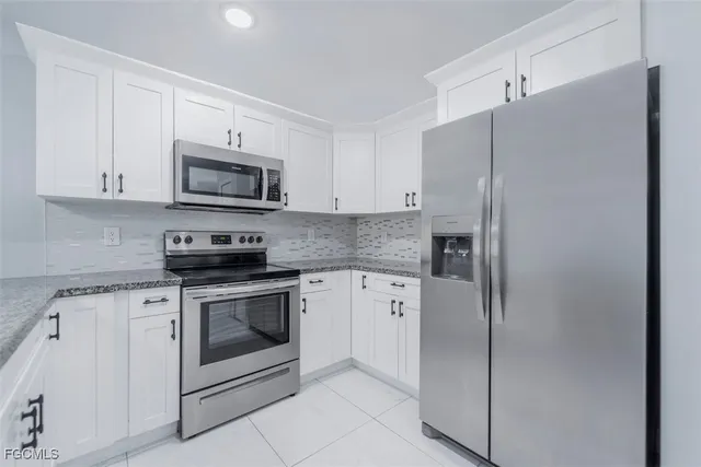 a kitchen with stainless steel appliances white cabinets white stove a microwave and a refrigerator